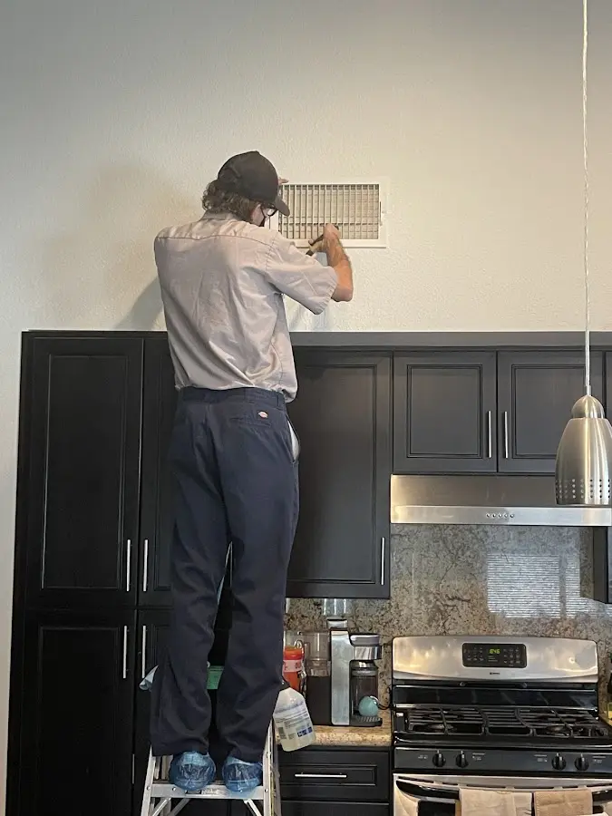 Technician inspecting an air vent during HVAC service in Pearland